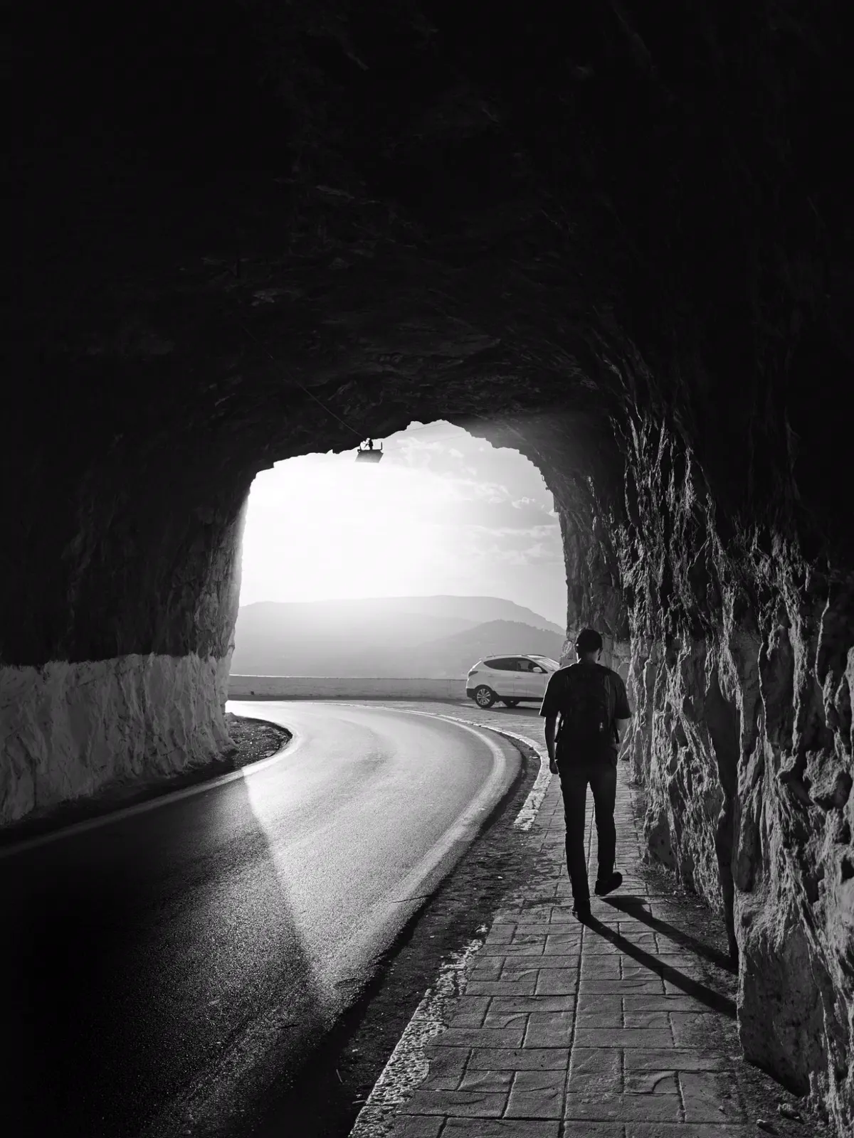 Walker leaving a rock-cut tunnel into the light